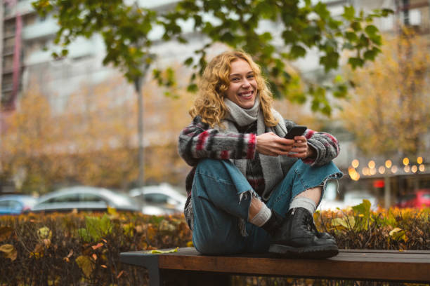 jovem sorridente na cidade segurando celular - telephone nature mobile phone autumn - fotografias e filmes do acervo