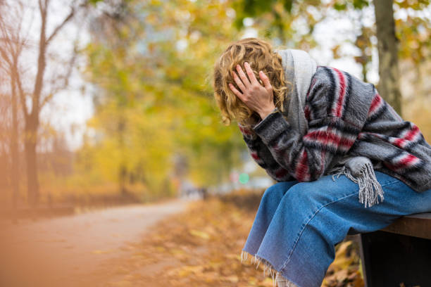 przygnębiona młoda kobieta siedząca na ławce w publicznym parku - frustration one person blond hair displeased zdjęcia i obrazy z banku zdjęć