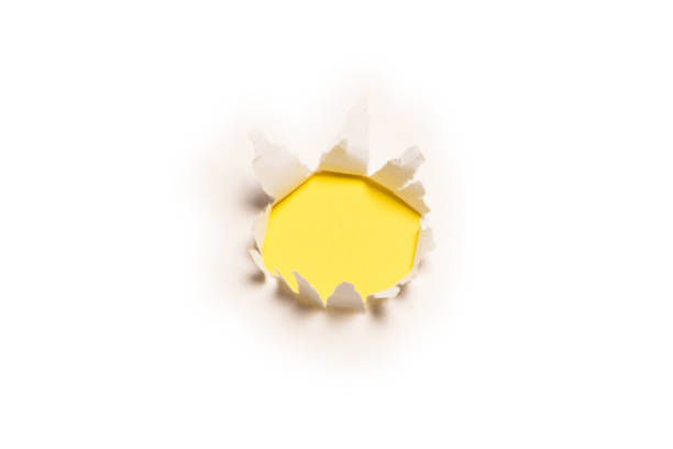 istock A hole in a white paper on a yellow background. 1355092164