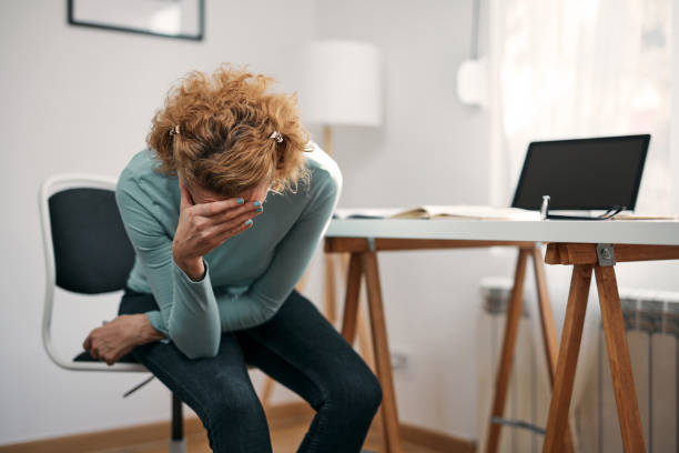 femme souffrant de spasmes d’estomac, de crampes, de maux de tête, de douleurs à la tête, de problèmes et de problèmes de travail à domicile. - se courber en avant photos et images de collection