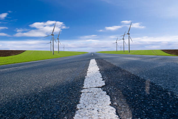 istock Asphalt road with blue sky and wind turbines 1355092475
