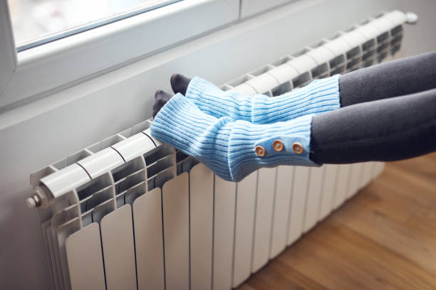 istock Woman's feet with woolen socks, enjoying inside home on the radiator. 1355092522