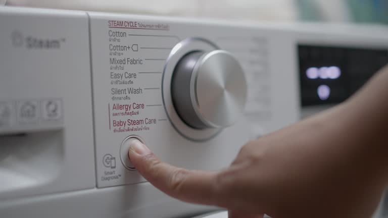 Close-up of human finger pushing the button to turn off a washing machine