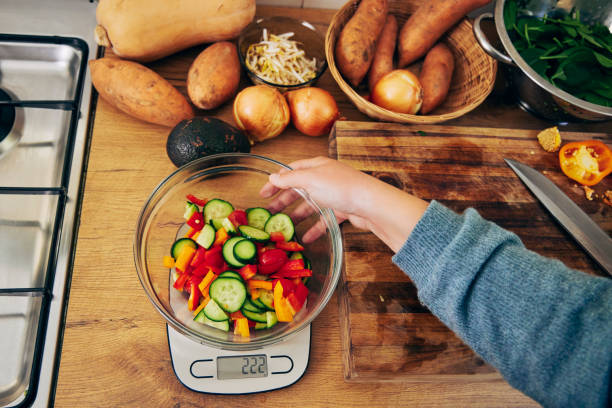 Shot of a young woman weighing a bowl vegetables A kitchen scale is so helpful kitchen scale stock pictures, royalty-free photos & images