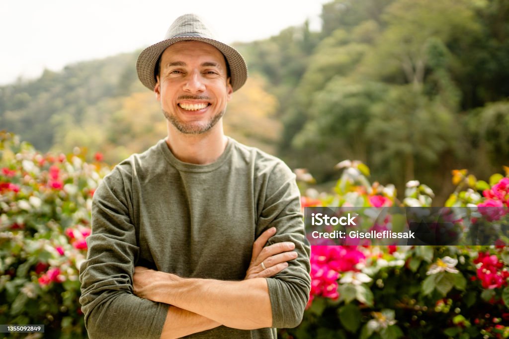Stylish young man smiling while standing with his arms crossed outside Portrait of a stylish young man smiling while standing with his arms crossed outside in summer Eclectic Style Stock Photo