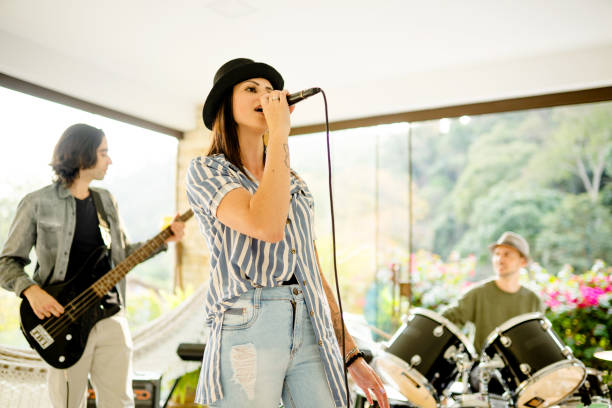 istock Young woman singing into a mic during a rehearsal with her band 1355093036