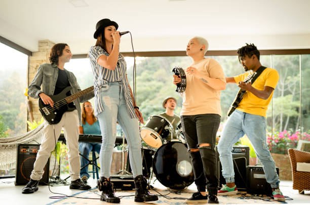 Diverse young band playing a song together in a home music studio Band of diverse young members playing a song together during a rehearsal session in a home studio performance group stock pictures, royalty-free photos & images