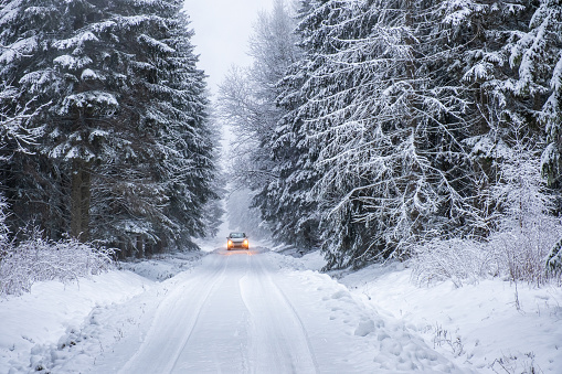 Car driving on a winter road in the forest
