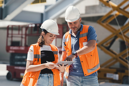 Civil Engineers Checking Works According To Project Using Digital Tablet At Construction Site