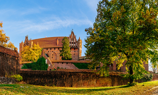 Malbork - The Castle of the Teutonic Order in a sunny autumn day. Blue sky on the background. Wall covered with ivy.