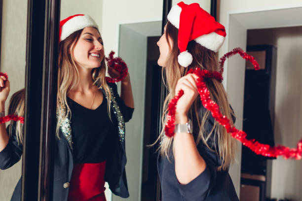 新年またはクリスマスパーティーの準備。スタイリッシュな衣装とサンタの帽子をかぶって鏡の前で踊る女性 - mirror women getting dressed dress ストックフォトと画像