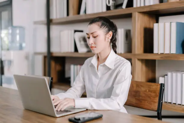Concentrated young beautiful businesswoman working on laptop in bright modern office,Work from home concept