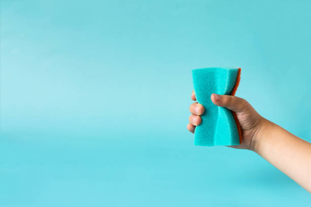 akcja ręka trzyma niebieską gąbkę na kolorowym tle. koncepcja mycia naczyń i czyszczenia - 5143 zdjęcia i obrazy z banku zdjęć