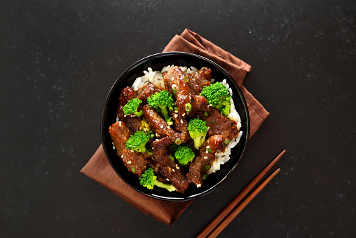 Beef and broccoli stir fry with rice on dark background. Top view, flat lay
