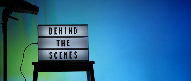 istock Behind the scenes text on Lightbox or Cinema Light box. Movie board light box on studio stair and light Snoot tripod on colors gradiant Background. Represent behind the scenes team is working on. 1355103952