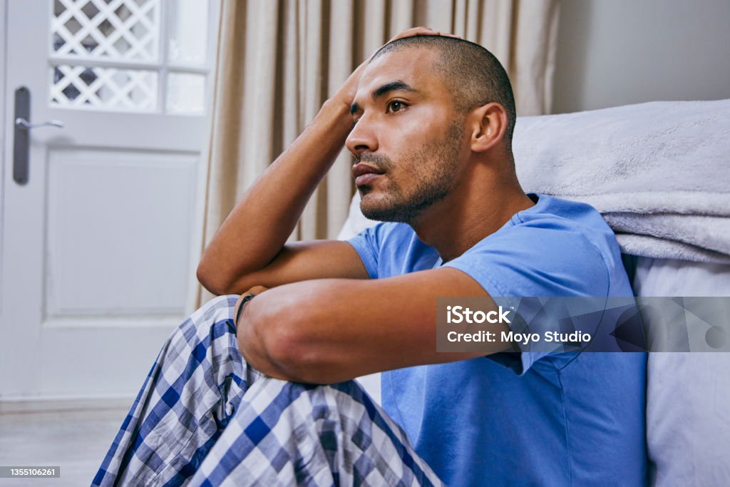 Shot of a young man looking unhappy in a bedroom at home It's okay to take some time to think Guilt Stock Photo