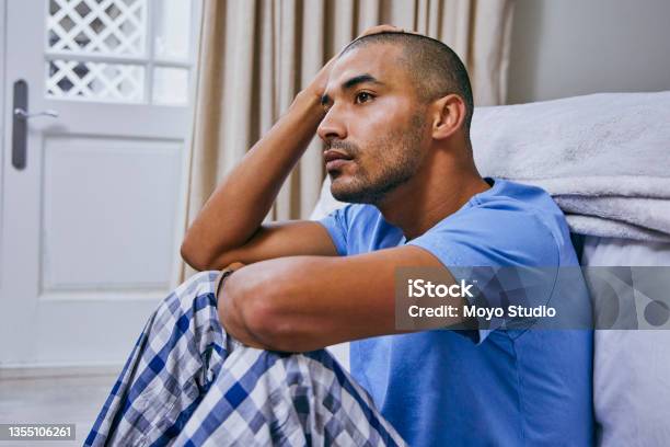 Shot Of A Young Man Looking Unhappy In A Bedroom At Home Stock Photo - Download Image Now