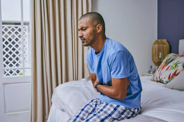 photo d’un jeune homme souffrant de maux d’estomac à la maison - belly ache photos et images de collection