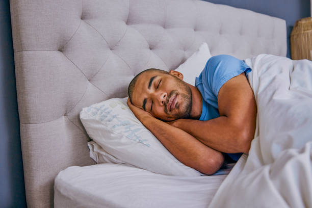 istock Shot of a young man sleeping in a bed at home 1355106331