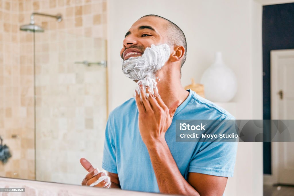 Shot of a young man applying shaving cream to his face in a bathroom at home This is calming Shaving Stock Photo
