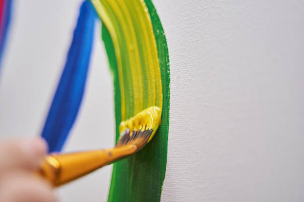 Professional art brush being in female hand while painting on canvas