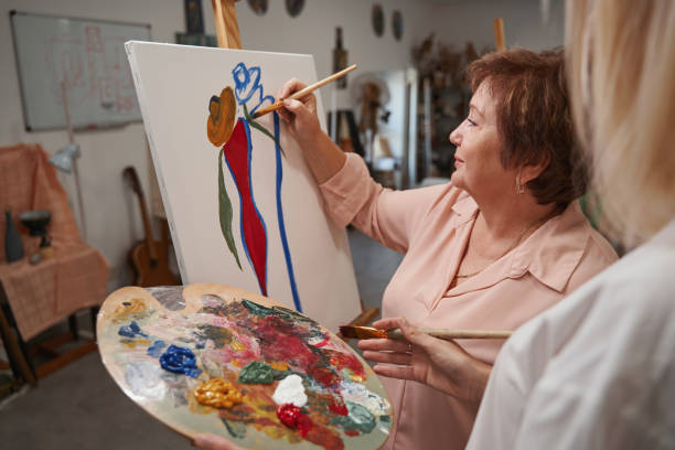 istock Close up of artist helping her aged student 1355107048