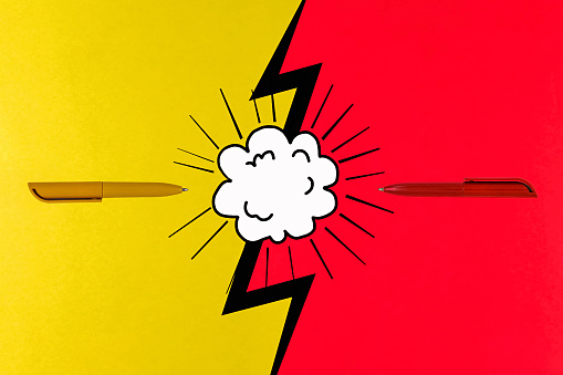 The concept of opposing views, on a bright yellow and red background. Cutting edge of the pen