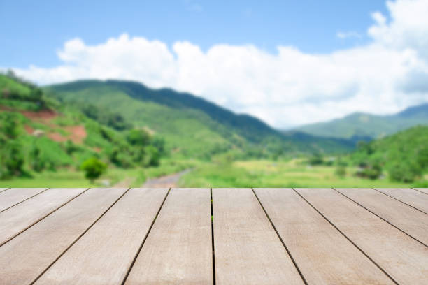 Empty old wooden top table in front of blurred beautiful mountain view, forest and cloud on blue sky at country side on clear day background. Can be used for display or montage for show your product. stock photo