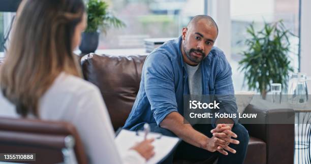 Cropped Shot Of A Handsome Young Man Looking Thoughtful While Sitting In Session With His Female Therapist Stock Photo - Download Image Now