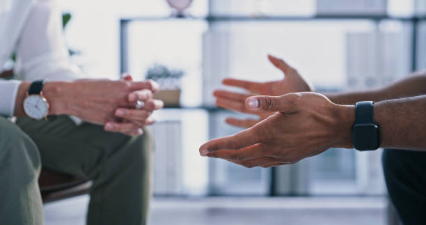 Closeup shot of an unrecognizable psychologist and patient's hands during a therapy session stock photo