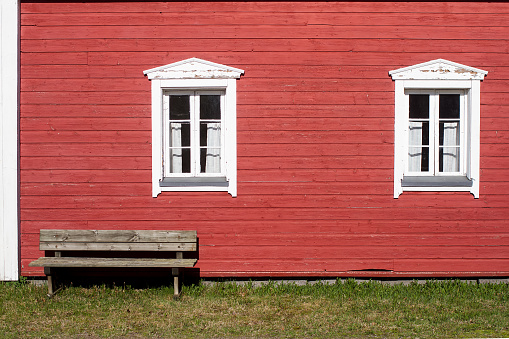 An exterior of an old wooden house on a summer day. The wooden bench is perfectly situated in the warm sunny spot.