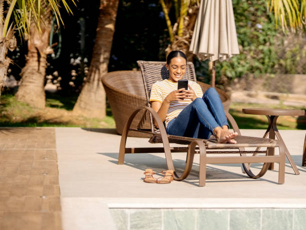 istock Woman relaxing at the poolside using mobile phone 1355114204