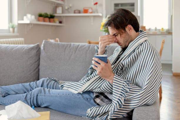 istock Ill Man Wrapped in a Warm Blanket Drinking Hot Tea at Home 1355115855