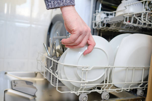 istock Man's hand taking the washed dishes from the dishwasher 1355118718