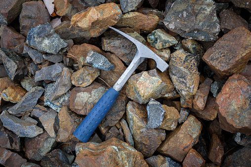 Chisel edge rock pick, geologist exploration tool over natural rocks background in abandoned chromite mine in Cyprus