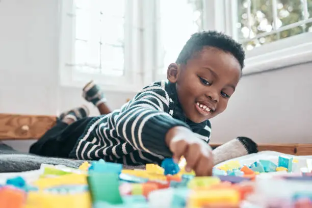 Photo of Shot of an adorable little boy playing with building blocks at home