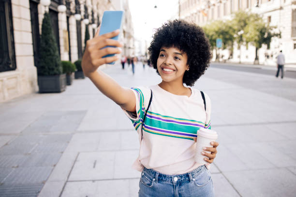 Portrait of a young African American woman on vacation walking and taking a selfie Portrait of a young African American woman on vacation exploring Madrid and taking a selfie. selfie madrid photos stock pictures, royalty-free photos & images