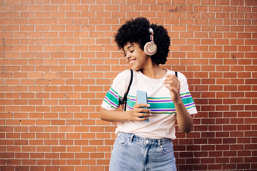 Portrait of a young African American woman on vacation in Madrid enjoying music.