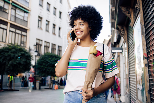 Portrait of a young African American woman on vacation exploring Madrid and talking on mobile phone.
