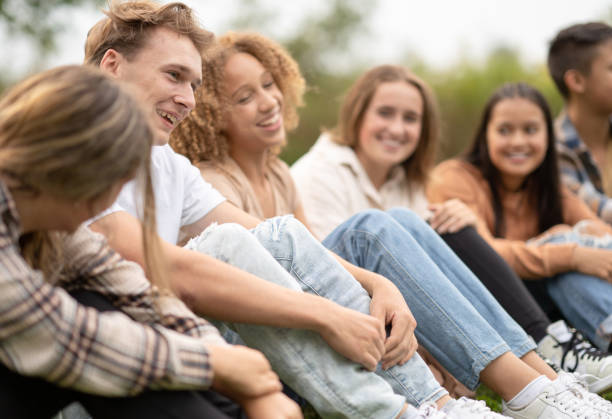 istock High School Students Sitting in a Line Outside 1355122334