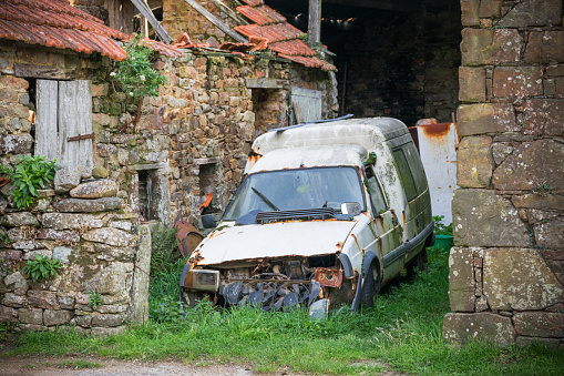 abandoned rusty car at a collapsed barn. This is a car wreck which can not be on the road again.