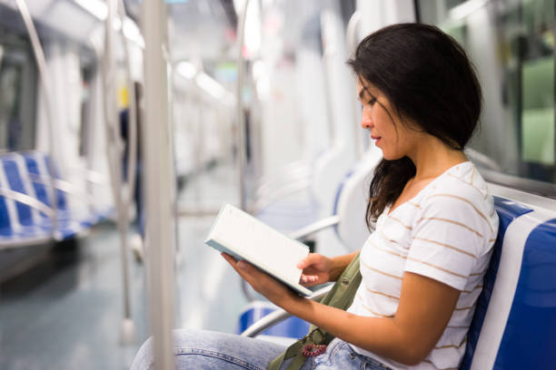 istock Oriental woman reading book in metropolitan train 1355127502