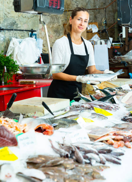 istock Female fishmonger offering sea bass 1355127616