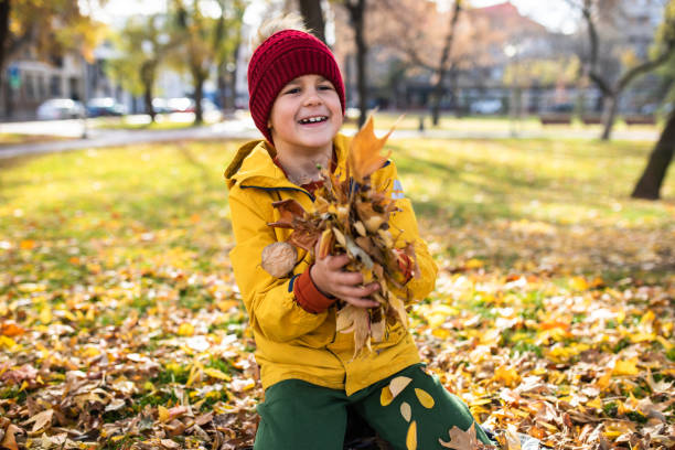 istock A cute boy playing with autumn leaves 1355127878