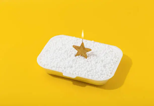 Burning candle in the form of a star on a white and yellow background