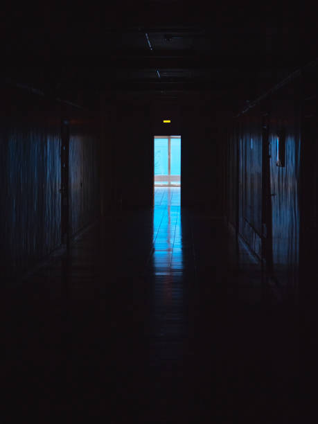 istock End of dark tunnel with magic blue light. Vertical view. Empty dark corridor in hospital laboratory. Blue light at the end of a dark corridor. 1355128849