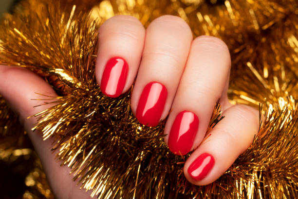 istock Hand with red nails with golden tinsel 1355131566