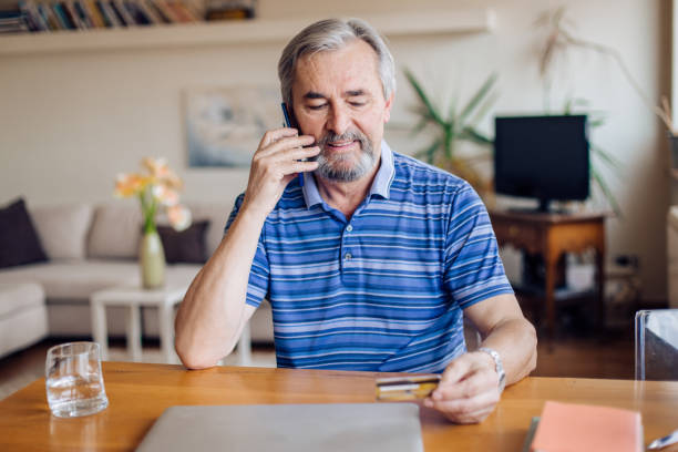 istock Senior man using mobile phone while holding credit card 1355131594