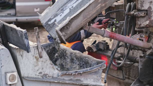 istock Fresh Cement Flowing Out of Mobile Concrete Mixer Truck While Contractor Operator is Distracted Using Smartphone 1355131682