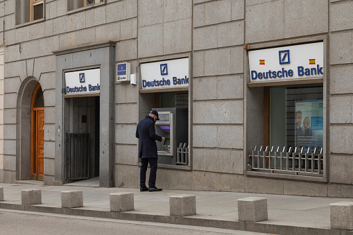 Madrid, Spain - Dec 27, 2020: A man withdraws money from a Deutsche Bank ATM, located in Carrera de San Jeronimo street, downtown area